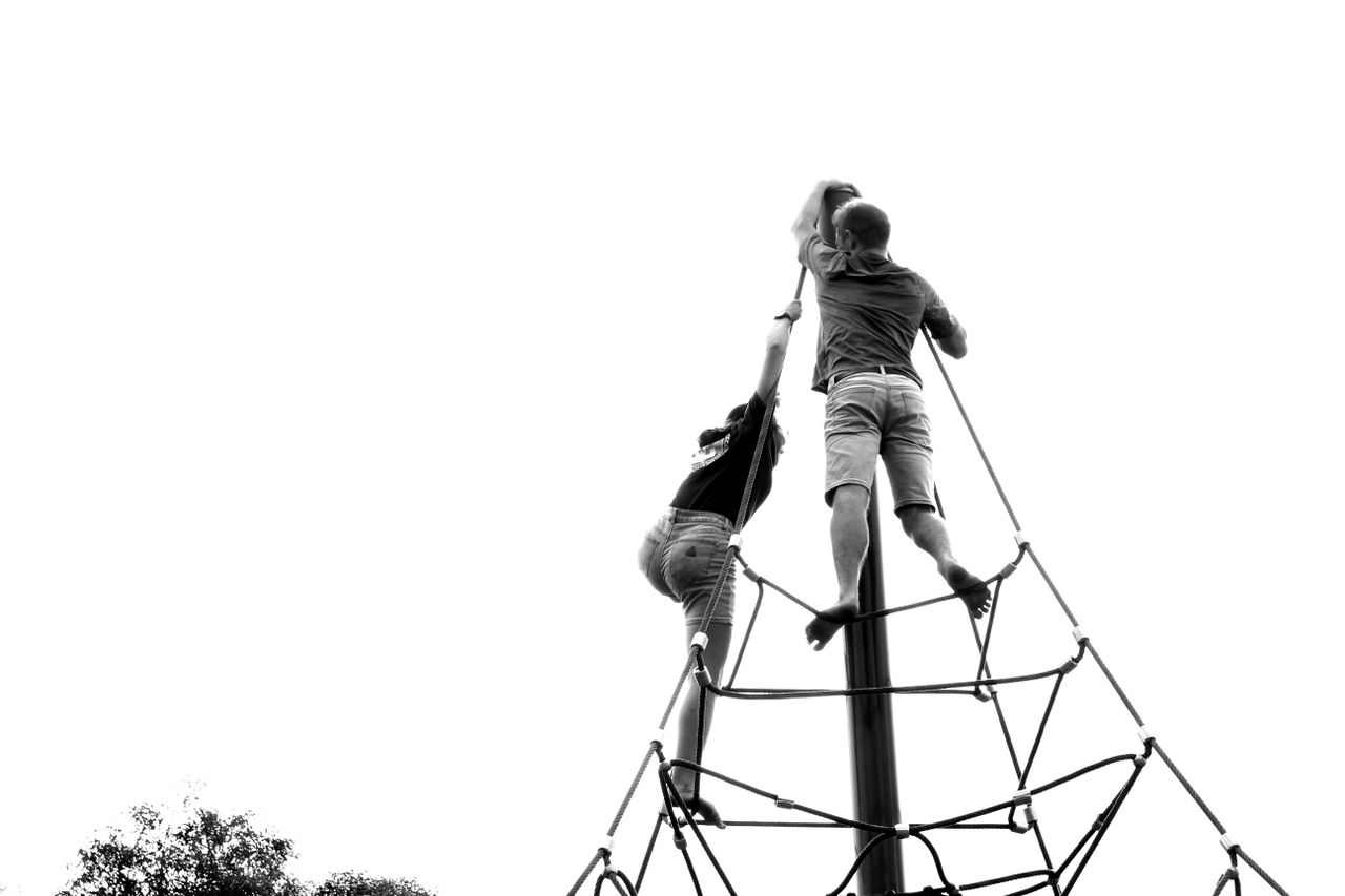 services-04 Two people climbing a playground rope structure in a black and white setting.