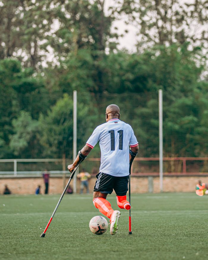 who-we-are Amputee soccer player with prosthetic leg in motion on grassy field, showcasing resilience.